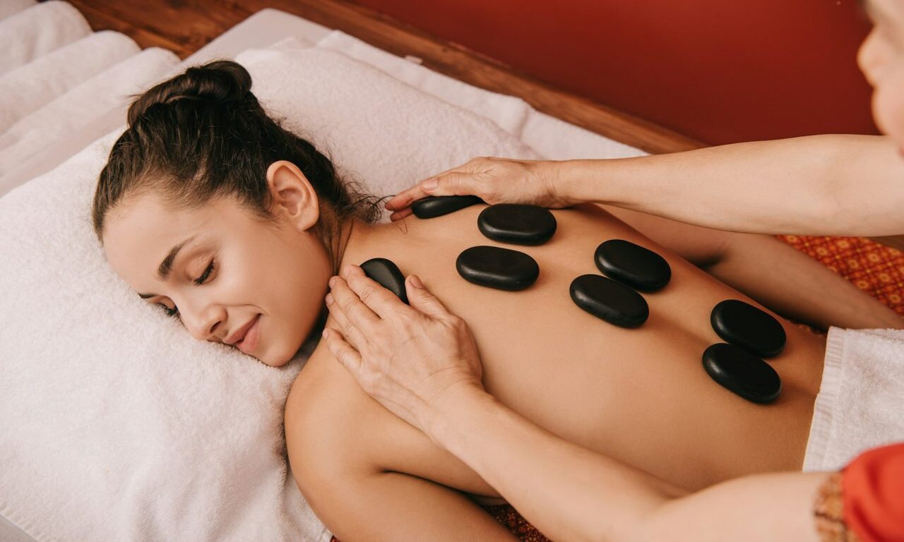 cropped-view-of-masseur-doing-hot-stone-massage-to-woman-in-spa-salon